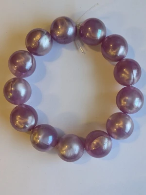 Armband med stora lila pärlor  - Jätte fint armband med stora lila pärlor. Elastiskt band gör det lätt att ta på och av. Jag har tillverkat armbandet själv 
