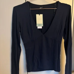 Marinblå v-ringad tröja från Gina Tricot - En marinblå långärmad tröja från Gina Tricot med v-ringning och figurnära passform. Tröjan är i ett supermjukt material. Den är endast testad.