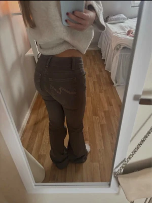 Bruna bootcut jeans med låg midja - Säljer ett par bruna jeans med bootcut-modell och låg midja. Byxorna har klassiska fickor bak med dekorativ söm och är tillverkade i ett mjukt bomullsmaterial. Storlek 32!❣️
