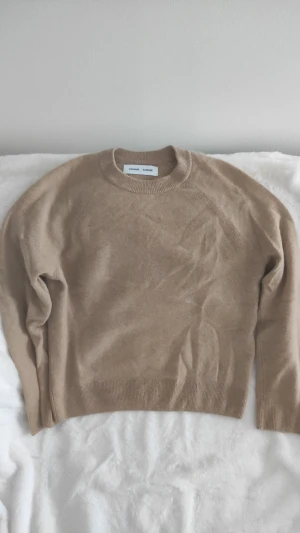 Stickad Kashmir Samsøe Samsøe - En klassisk beige stickad tröja från Samsøe Samsøe. Tröjan har en enkel och stilren design som passar perfekt till alla typer av outfits. Tillverkad i Kashmir material. Nypris 2400. Använd fåtal gånger och säljer då jag har två. 
