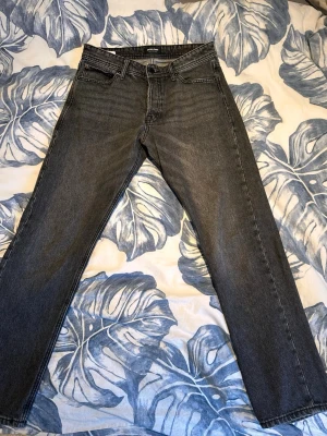 Grå loose fit jeans Jack & Jones 32/32 - Säljer ett par grå loose fit jeans från Jack & Jones i storlek 32/32. Jeansen har klassisk femficksdesign, raka ben och en avslappnad passform. Perfekta för dig som gillar en chill och bekväm stil. Materialet är slitstarkt jeans.