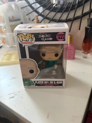 Player 001 - Squid Game Funko Pop - Bilderna visar en Funko Pop-figur från Squid Game, Player 001: Oh Il-Nam. 