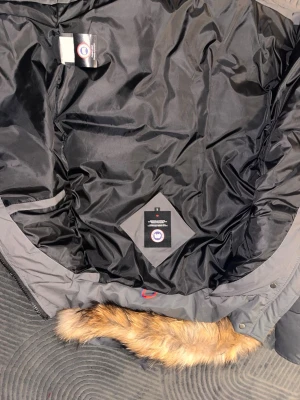 Cardigan - Säljer en svart dunjacka från Canada Goose i storlek S. Jackan har en stor huva med äkta pälsdetalj, quiltad design och dragkedja. Perfekt för kalla vinterdagar och riktigt varm. Klassisk look med diskret logga på insidan.