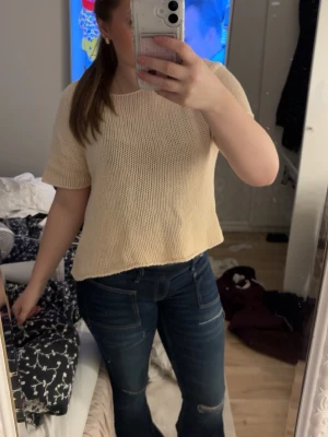Beige stickad topp från Vila - Säljer en beige stickad topp från Vila i storlek S/M. Toppen har korta ärmar, rund halsringning och en synlig dragkedja i nacken. Perfekt för dig som gillar en enkel och chill stil med lite struktur i materialet.