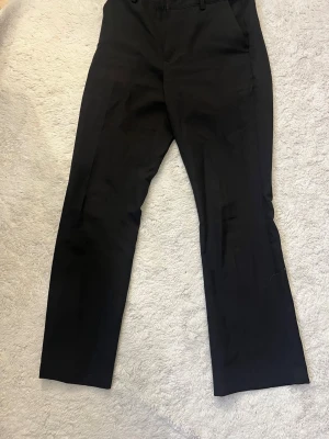 Vilma petite kostymbyxor - Kostymbyxa med medelhög midja, raka smala ben som är lätt utsvängda nedtill och pressveck. Linning med hällor samt dold ögla, knapp och dragkedja framtill. Byxan har snedställda sidofickor fram och dekorativa stolpfickor bak. Petite längd. Använd endast 2 gånger  Ordinarie pris 499