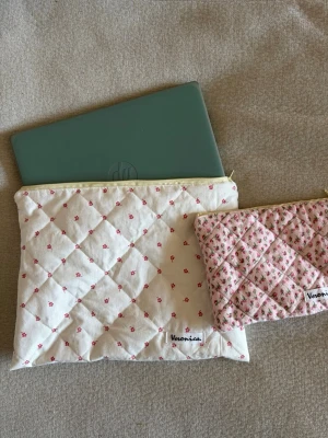 Quiltad datafodral med blommor - Superfint handgjort datafodral från Veronica. i vitt quiltat tyg med små blommor 🌷Fodralet har praktiska fack inuti samt pennhållare, perfekt till smink, pennor och datorsladdare. Mjukt vadderat så det skyddar bra✨ Sydd med 100% återbrukade material – både snyggt och hållbart ♻️  Passar 13 tum dator (30x21 cm) eller stor iPad. Välj tyg på sista bilden🩷