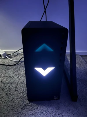 Svart stationär dator med LED-belysning - Säljer en svart stationär dator med modern design och LED-belysning på fronten. Datorn har en kompakt och stilren form med märkning '15L' på sidan. Perfekt för gaming eller arbete, och passar snyggt in i hemmets setup.