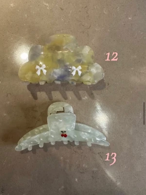 Två hårklämmor i pastellfärger vit blå gul - Säljer två hårklämmor! Den ena är gul vit och blå pastell med vita rosetter, den andra är vitt med ett litet rött körsbär. 1 för 95 2 för 160!
