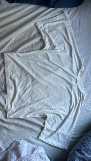 Vit oversized t-shirt i viskos - Enkel och stilren vit t-shirt med loose passform och korta ärmar. Tillverkad i viskos, perfekt för en avslappnad look. Klassisk rund halsringning och utan tryck eller mönster.