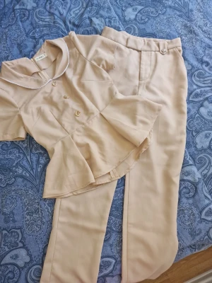 Beige set med topp och byxor - Sött set beige blus och matchande byxa. En chic look till sommaren. S I storlek men liten I storleken så skulle säga passar XS