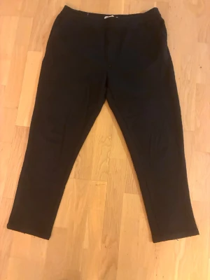 Svarta mjukisbyxor från Zara - Svarta mjukisbyxor från Zara med dragsko i midjan och avslappnad passform. Byxorna har raka ben och är tillverkade i ett mjukt och bekvämt tyg, perfekta för chill dagar. Snygg och enkel design som funkar till det mesta.