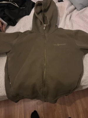 Sail racing hoodie L men passar bra på M - Olivgrön hoodie med dragkedja från Sail Racing. Klassisk design med huva och logotyp broderad på bröstet. Mjuk bomullskänsla och ribbade muddar vid ärmslut och nederkant. Perfekt för en avslappnad och cool look.