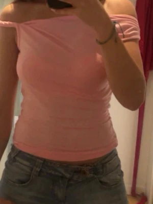 Rosa offshoulder topp - Snygg rosa offshoulder topp med tight passform. Perfekt för dig som gillar en enkel men trendig stil. Toppen är ärmlös och har en mjuk, stretchig känsla som sitter skönt mot kroppen.