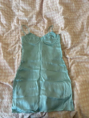 Blå klänning  - Blå satin klänning Zara. Storlek s men väldigt liten i storleken. Byglarna sticker även ut men de kan man tejpa eller ta ut helt 