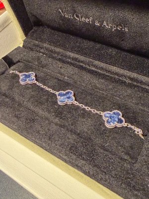 VCA 5 motif pietersite 18k doppat armband - VCA 5 motif 18k vitt guld doppat armband med riktiga stenar! Säljer då den inte kommer till användning. Tål vatten iom 18k doppningen! Gjord på beställning åt mig, men kom aldrig till användning tyvärr! Haft den i ca. 1 år nu. Kommer med förpackningen på bilden! 