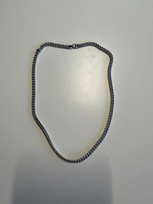 Silver kedjehalsband - Säljer ett stilrent halsband i silverfärgad metall med klassisk kedjedesign. Halsbandet har en robust och enkel låsning som gör det lätt att ta av och på. Perfekt för dig som gillar minimalistiska accessoarer.