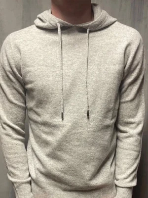 Kashmere hoodie  - En stilren ljusgrå hoodie med huva och långa ärmar. Hoodien har dragsko med metalländar och är tillverkad i ett mjukt, stickat material som känns skönt mot huden. Perfekt för en avslappnad look och enkel att matcha med andra plagg.