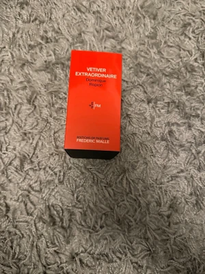 Vetiver Extraordinaire parfym 50ml - Parfymen Vetiver Extraordinaire av Dominique Ropion från Frédéric Malle. Kommer i en snygg röd och svart kartong. Eau de Parfum, 50 ml. Lyxig och modern doft för dig som gillar exklusiva parfymer.