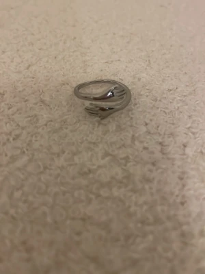 Silvrig hug ring - Säljer en silvrig ring med två armar som kramas. 🌸den är justerbar så den passar alla storlekar, har knappt använt den