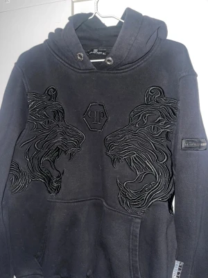 Svart hoodie med tigerbrodyr - Snygg svart hoodie från ett känt märke. Passar även L