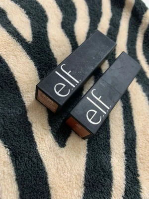 e.l.f. O Face Satin Läppstift duo - Två e.l.f. O Face Satin Lipstick i färgerna 'No Doubt' och 'Limitless'. Läppstiften har en matt svart fyrkantig hylsa med tydlig logga. Satin-finish ger en mjuk och krämig känsla på läpparna. Perfekt för dig som gillar naturliga och nude-tonade nyanser.