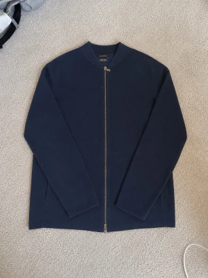 Mörkblå ziptröja Massimo Dutti - Mörkblå ziptröja från Massimo Dutti i mjuk bomull. Tröjan har rak passform, rundad halsringning och hel dragkedja framtill. Enkel och stilren design som ger en clean look.