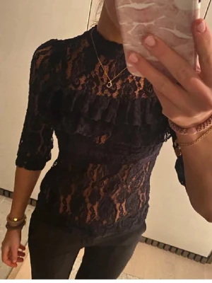 Svart spetsblus med volangdetalj - Snygg svart spetsblus med volangdetalj över bröstet och trekvartsärm. Strl Xs 250 kr❤️