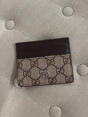 Ett kortfodral i  brun - Snyggt kortfodral från  med bruna läderdetaljer. Plånboken har flera kortfack  samt en liten silverfärgad logga framtill. Perfekt för dig som vill ha en stilren och lyxig accessoar.