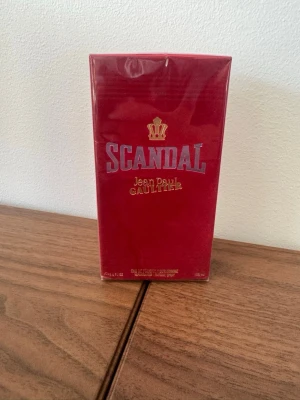 Scandal parfym Jean Paul Gaultier - Scandal parfym från Jean Paul Gaultier i en lyxig röd förpackning med gulddetaljer och en krona på framsidan. Förpackningen är rektangulär och har en elegant, modern design som sticker ut på hyllan. Perfekt för dig som gillar exklusiva dofter och snygg design.