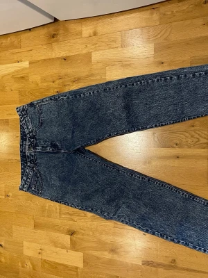 Drdenim Mörkblå raka jeans stl W30 L34 - Säljer ett par mörkblå raka jeans Dr denim med klassisk femficksmodell och hög midja. Jeansen har en tvättad look och är tillverkade i kraftig denim. Perfekta för dig som gillar en tidlös och avslappnad stil.