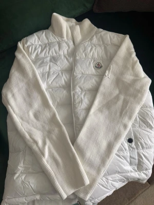 Vit dunväst från Moncler - Snygg vit dunväst från Moncler med ribbstickade ärmar och hög krage. Helt ny moncler cardigan och aldrig använd med nfc och prislapp!!