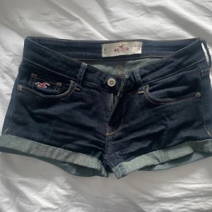low waist shorts Hollister - Snygga mörkblå denimshorts från Hollister med uppvikta benslut och klassiska kontrastsömmar. Shortsen har fem fickor, knappgylf och en liten logga på ena fickan. Perfekta för varma dagar och enkel att matcha. strl 24 vilket motsvarar xs