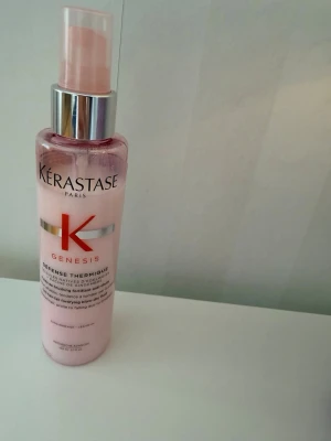 Kérastase Genesis Défense Thermique - Värmeskyddande spray från Kérastase Genesis-serien i en rosa plastflaska med pump. Produkten är framtagen för att stärka och skydda håret mot värmeverktyg och minska risken för håravfall.