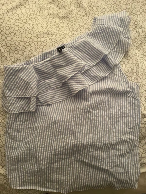 Randig oneshoulder topp Vero Moda - Säljer en ljusblå och vit randig oneshoulder topp från Vero Moda. 