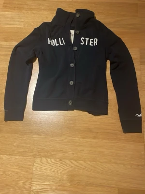 Mörkblå hoodie från Hollister - Mörkblå Hollister Hoodie/cardigan. Storlek M. Armmått 62cm breddmått 44cm 