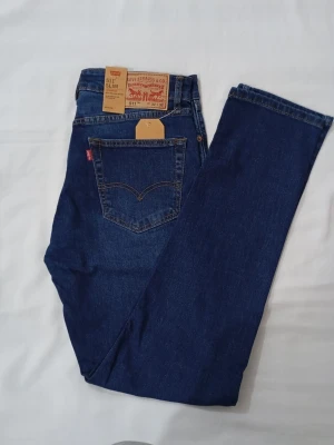 Levi's 511 Slim mörkblå jeans - Säljer ett par Levi's 511 Slim jeans i mörkblå denim. Klassisk femficksmodell med rakt ben och normal midja. Jeansen har den ikoniska röda Levi's-lappen på bakfickan och patch i läder bak i midjan. Perfekta för en clean och stilren look.