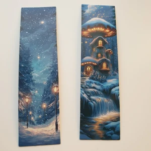 Två vinterinspirerade bokmärken - Säljer två bokmärken med magiska vintermotiv. Ena visar en snötäckt skogsväg med gatlyktor och stjärnklar himmel, den andra ett sagolikt hus med svampformat tak och vattenfall i vinternatt. Tryckta på tjockt papper i blå toner, perfekta för bokälskare. Skick: ny/oanvänd  Motiv på ena sidan, vit baksida  Storlek: ca 15×3cm