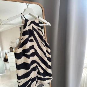 Zebramönstrad linnetopp från hm - Snygg ärmlös linnetopp med zebramönster i svart och vitt. Toppen har hög halsringning och tunna axelband, vilket ger en trendig och luftig look. Från hm. Superfin till alla olika tillfällen. 