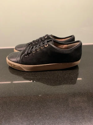 Lanvin - Stilrena svarta lanvins. Skorna har svarta skosnören, metallöljetter och en beige sula som ger en snygg kontrast. Lite slitna under. Perfekta för dig som gillar en clean och klassisk look. Storlek UK 9. Storlek 43-44 i mycket bra skick. Skickas med dustbag.