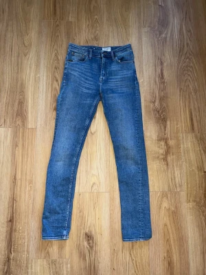 Blå slim fit jeans från Weekday - Snygga blå slim fit jeans från tiger of sweden med klassisk femficksdesign och normalhög midja. Jeansen har en lätt tvättad look och raka ben. Tillverkade i ett mjukt denimtyg som ger en skön passform. Perfekta till en avslappnad stil.