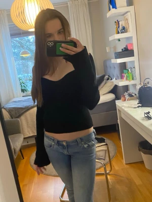 Svart croppad långärmad topp - Tröjan sitter som S. Säljer en svart topp med lång ärm och v-ringad hals. Toppen har en slim passform och är perfekt för dig som gillar en enkel men snygg stil. Passar till både jeans och kjol.