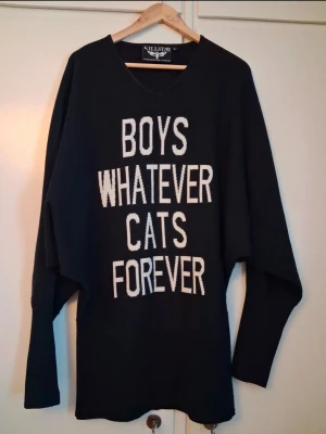 Svart Killstar tröja med text - Cool svart tröja från Killstar med vit statement-texten 'BOYS WHATEVER CATS FOREVER' på framsidan. Oversized passform med långa ärmar och v-ringad hals. Perfekt för dig som gillar edgy stil och katter.