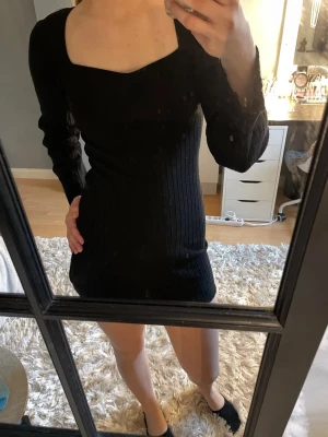 Svart ribbad kortklänning - Snygg svart ribbad kortklänning med lång ärm och fyrkantig urringning. Klänningen har en tight passform och är perfekt för dig som gillar en stilren look. Materialet känns mjukt och följsamt mot kroppen. Älskar men kan inte ha längre. Ej bra pris skriv. Skitter som både Xs och S
