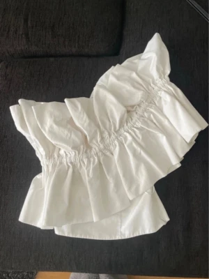 Vit volangig offshoulder topp - Säljer en vit offshoulder topp med volanger och resårdetaljer. 