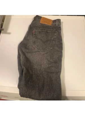 Grå Levi's 501 jeans - Säljer ett par klassiska grå Levi's 501 jeans i rak modell. Jeansen har fem fickor, knappgylf och den ikoniska läderlappen bak i midjan. Tillverkade i slitstark denim med vintage vibe och snygg tvättad look. Storlek W28 L32 passade ej mig 