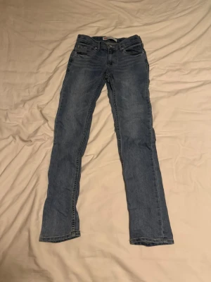 Blå jeans från Levi's - Säljer ett par klassiska blå jeans från Levi's,barn  Jeansen har en ljus tvätt och är tillverkade i slitstark denim. Perfekta för en avslappnad och tidlös stil.