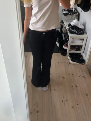 Svarta utsvängda jeans - Säljer ett par svarta jeans med utsvängda ben och klassisk femficksmodell. Jeansen har hög midja och är i stretchigt denimtyg som sitter snyggt. Perfekta för dig som gillar en trendig och bekväm stil. Storlek 34, säljer då dom är lite för korta för mig som e 170. Uppsprätta längst ner mer väldigt fint 