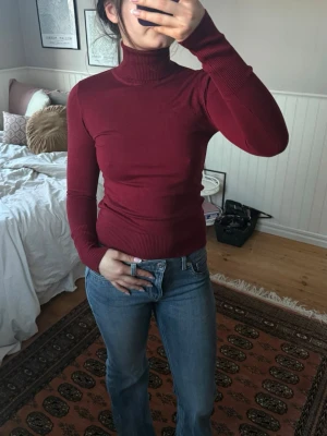 Vinröd polotröja från Stradivarius  - Säljer en vinröd stickad polotröja från Stradivarius. Tröjan har långa ärmar med ribbade muddar och hög polokrage. Materialet är mjukt och följsamt, perfekt för lager på lager. Enkel och stilren design som passar till mycket. Oanvänd.