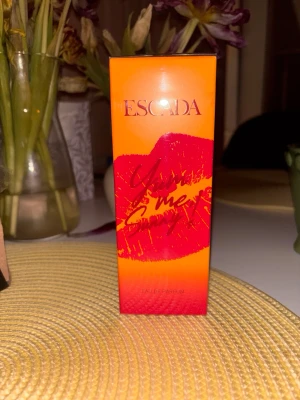 Escada You Me & Sexy Eau de Parfum - Nyhet från Escada i en snygg orange och röd förpackning med ett stort läppavtryck och texten 'You Me & Sexy'. Eau de Parfum, 50 ml. Boxen har en modern och färgstark design som sticker ut i badrumsskåpet. 