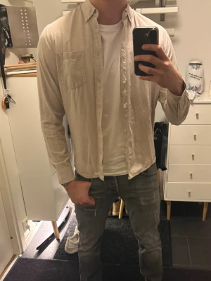 Beige linne skjorta från dobber  - Stilren beige linne skjorta från dobber i mjukt linnestyg. Skjortan har klassisk krage, bröstficka och knäppning framtill. Perfekt för en avslappnad men snygg look. Långärmad och med normal passform.